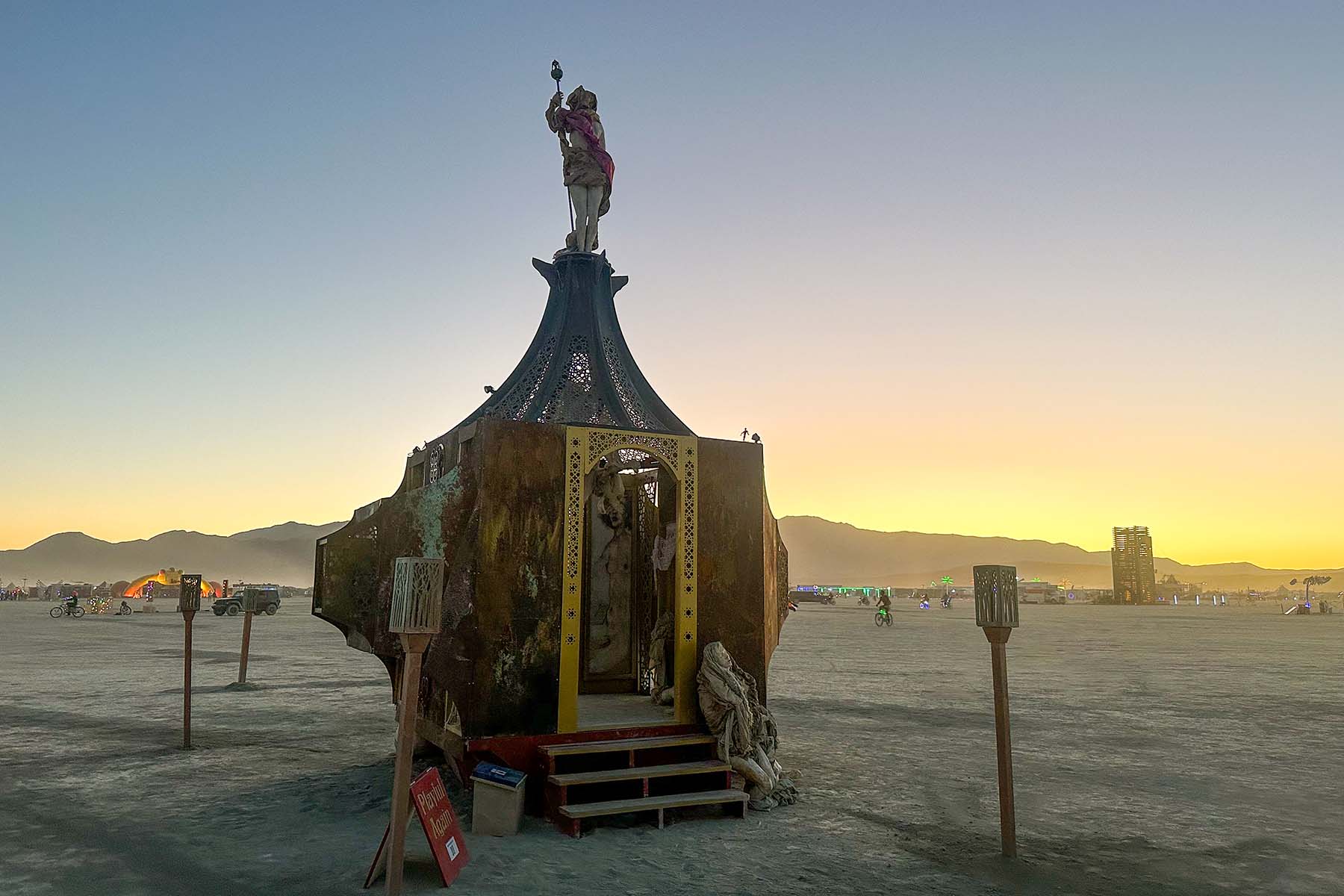 Playful Again silhouetted against a golden sunset on the open playa