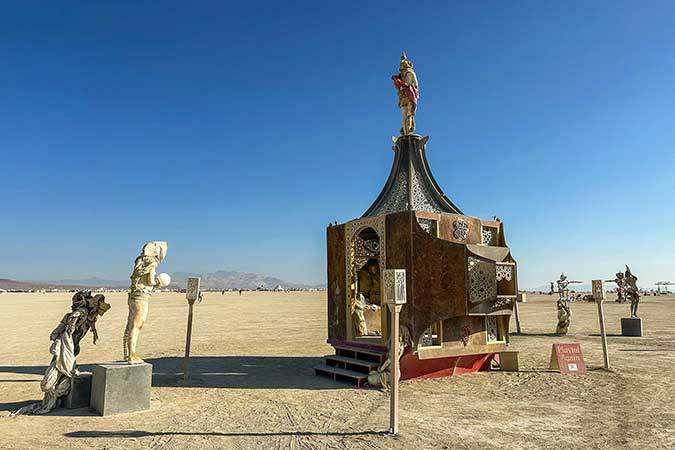 Playful Again by day, its rust-colored pavilion and cast figures on plinths spread across the playa