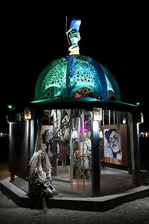 Secretly Abandoned Spaces at night with its teal-lit lattice dome and a long-haired cast figure seated on the front step and portrait