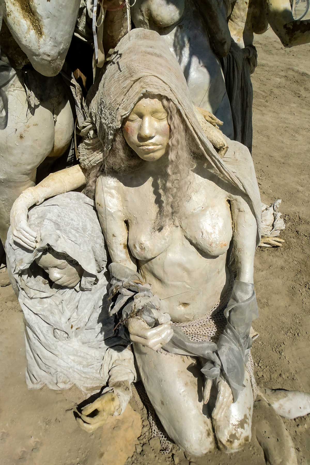 Cast figure of a woman with long hair kneeling at the base of Womantree, held among other draped figures