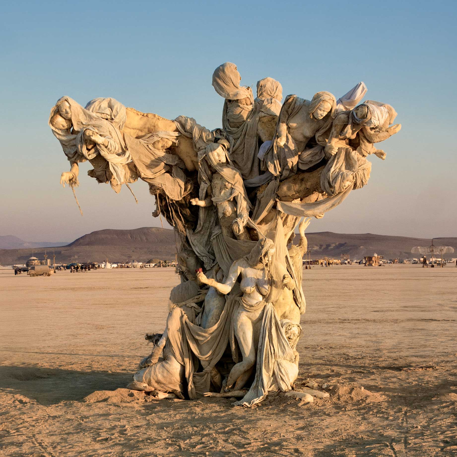 Womantree in golden evening light, its broad canopy of figures spread wide above the playa