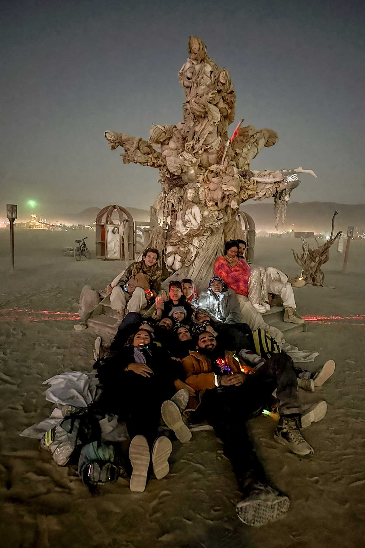 A group of visitors gathered at the base of Womantree at dusk