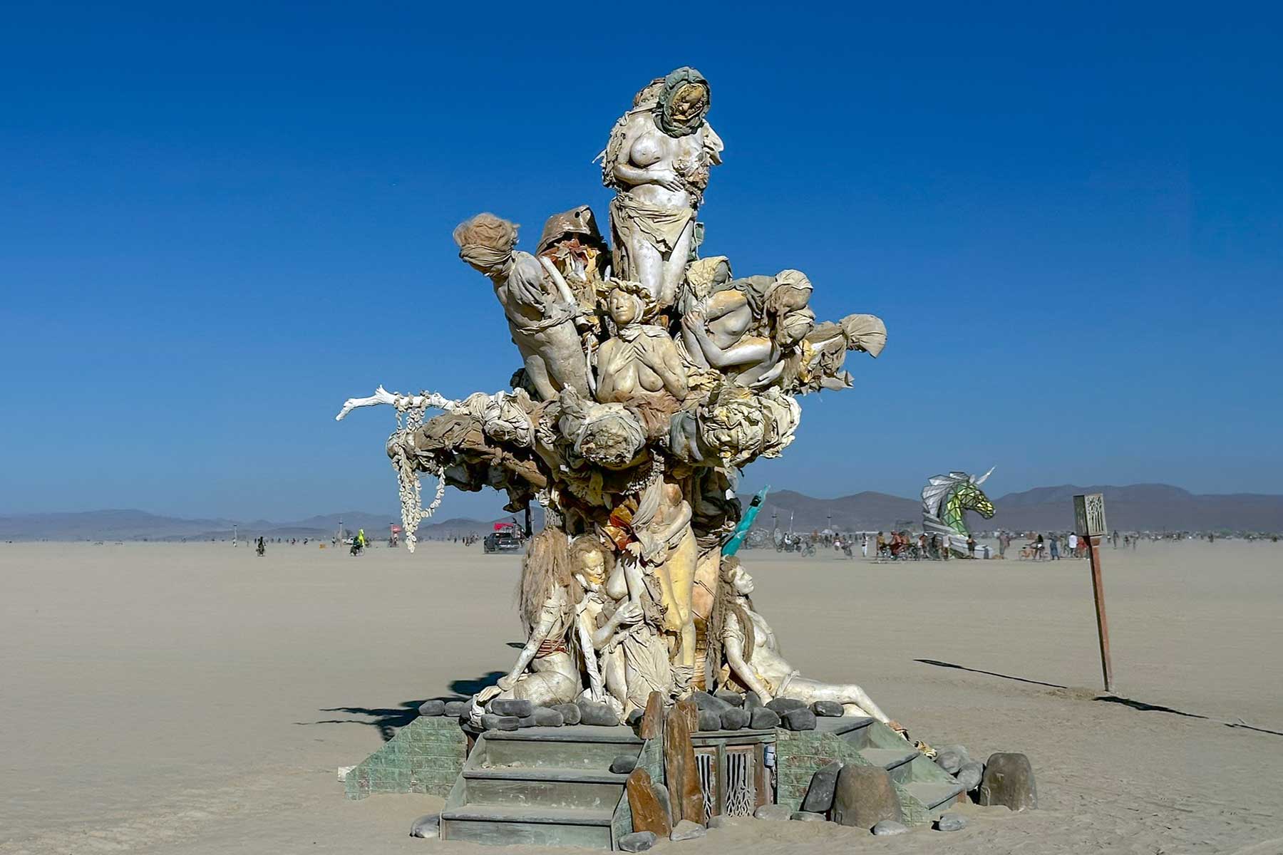 Womantree standing on the open playa under a deep blue sky at Burning Man 2024