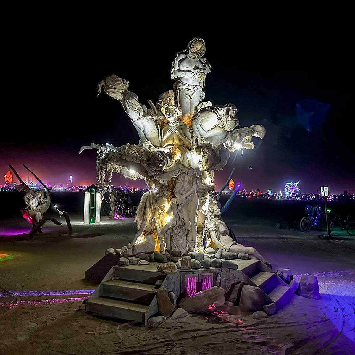 Womantree at night, its cast figures lit from below against the dark playa at Burning Man 2024