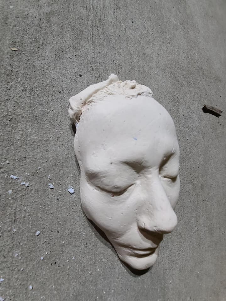Single plaster face cast lying on concrete