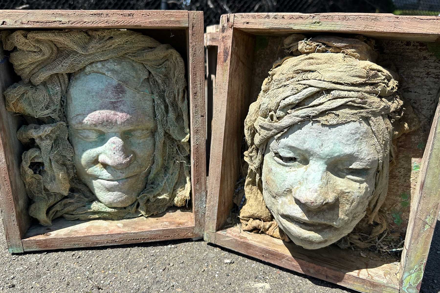 Two boxed face casts wrapped in sculpted fabric, side by side