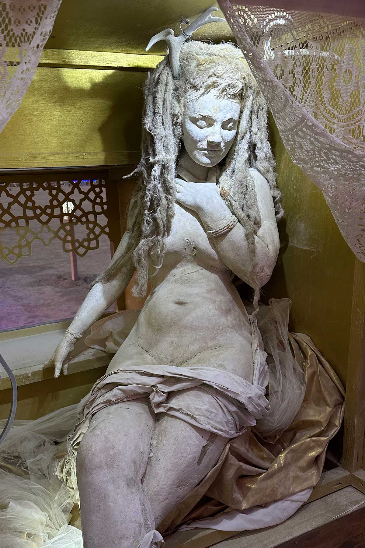 Seated cast figure of a woman with long hair, partially draped in cloth