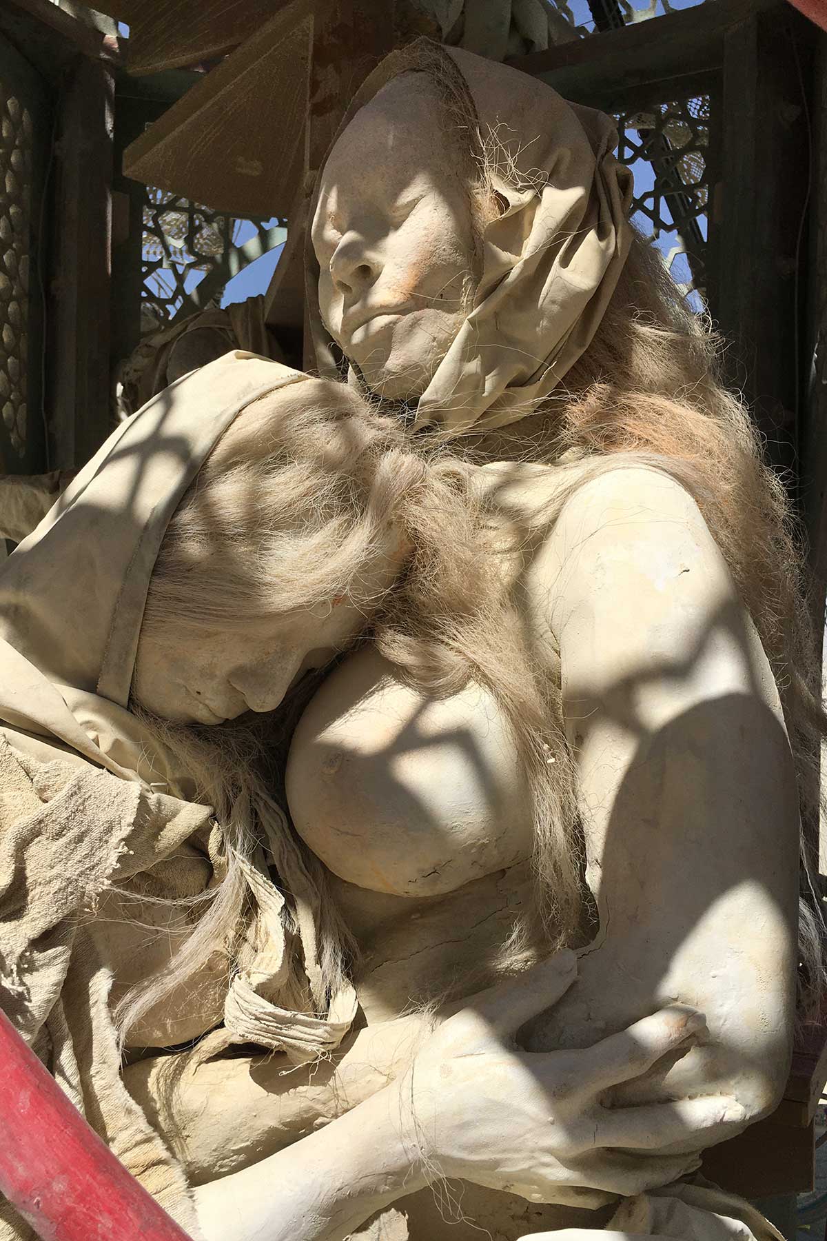 Cast figure of a woman wrapped in fabric, dappled with shadow from a lattice