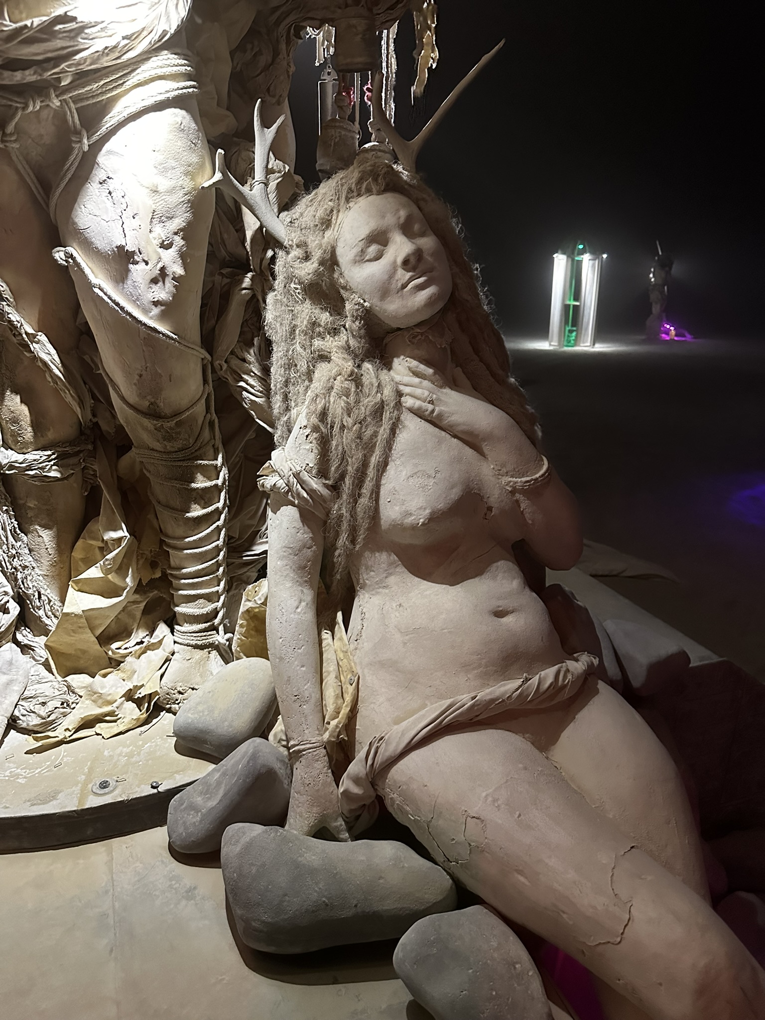 Reclining cast figure of a woman, lit at night inside an installation